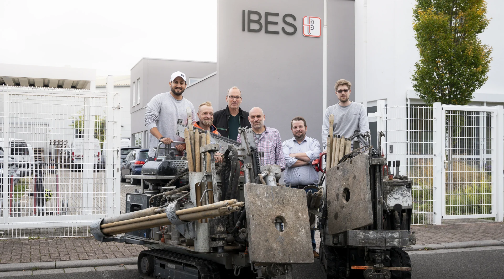 Gruppe von Männern vor dem IBES Gebäude mit bei zwei Maschinen, die für Bohrarbeiten verwendet werden.